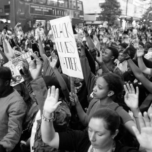 Black Lives Matter protesters kneel and raise their hands in London's Oxford Street on July 8, 2016