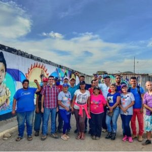 Luisa Cáceres communards assembled beside communal mural